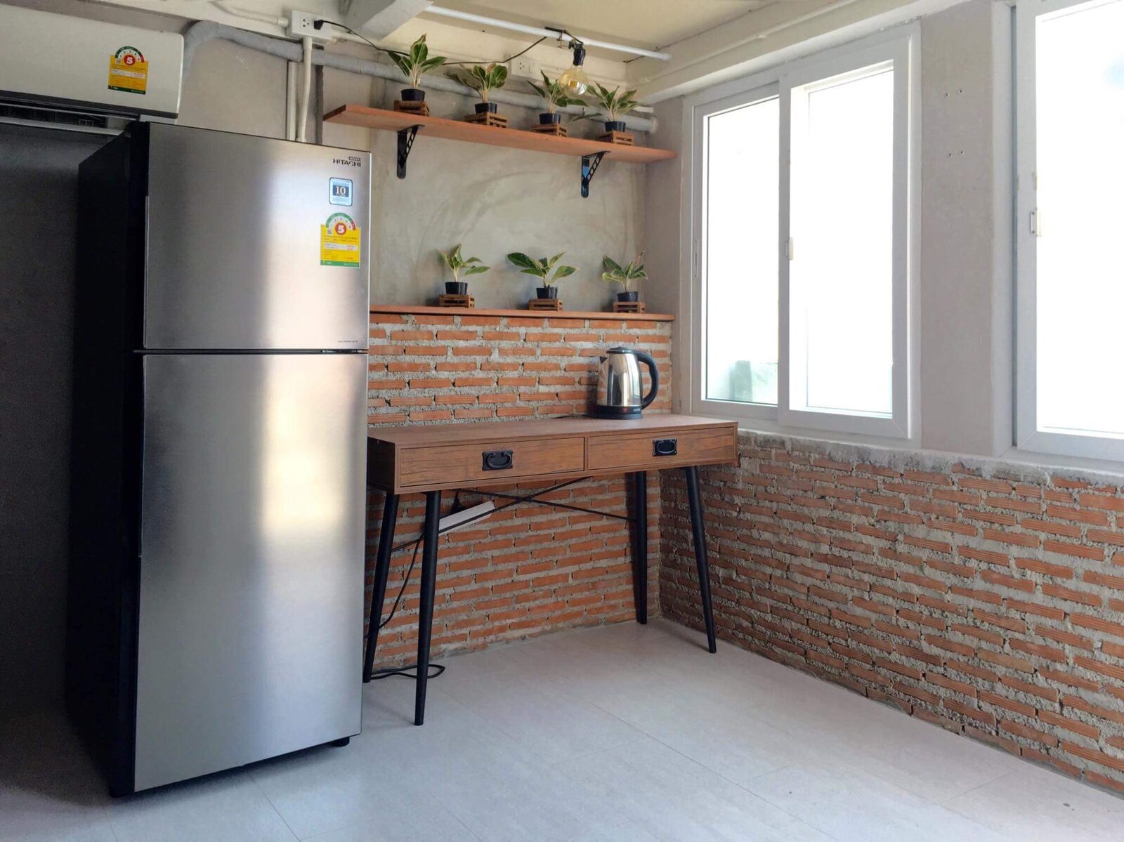 Rooftop Apartment kitchenette with fridge, desk, and brick wall