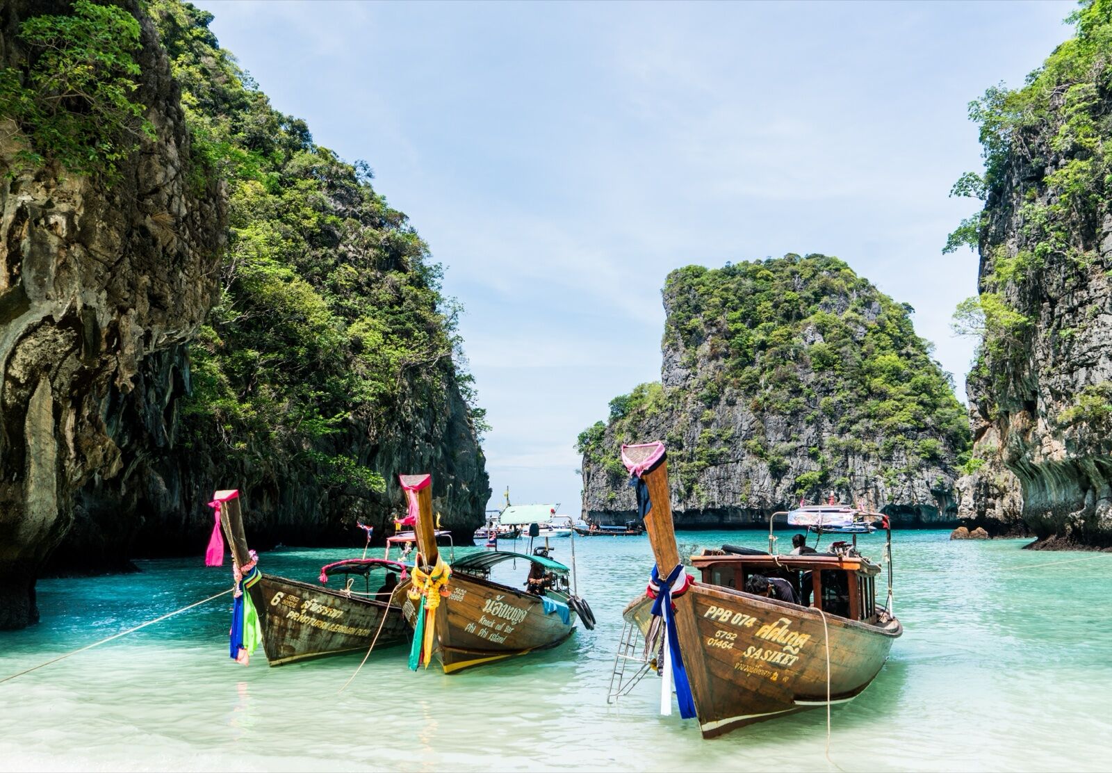 Longtail boats in turquoise lagoon surrounded by limestone cliffs, Phuket Thailand